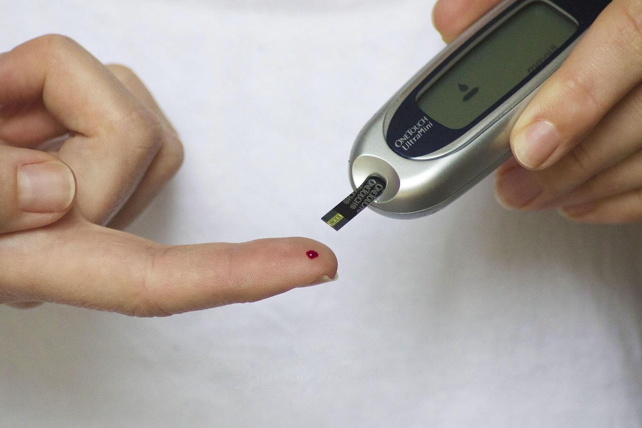 Accu-Chek glucometer sitting next to another blood sugar machine on a white table