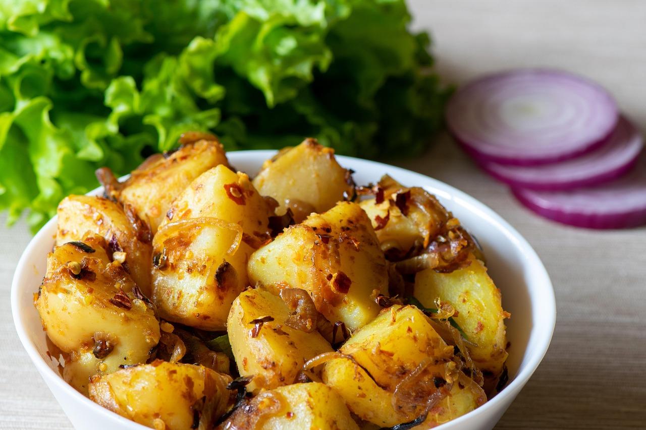 A dish of cooked cauliflower and potato sabzi garnished with fresh cilantro and spices