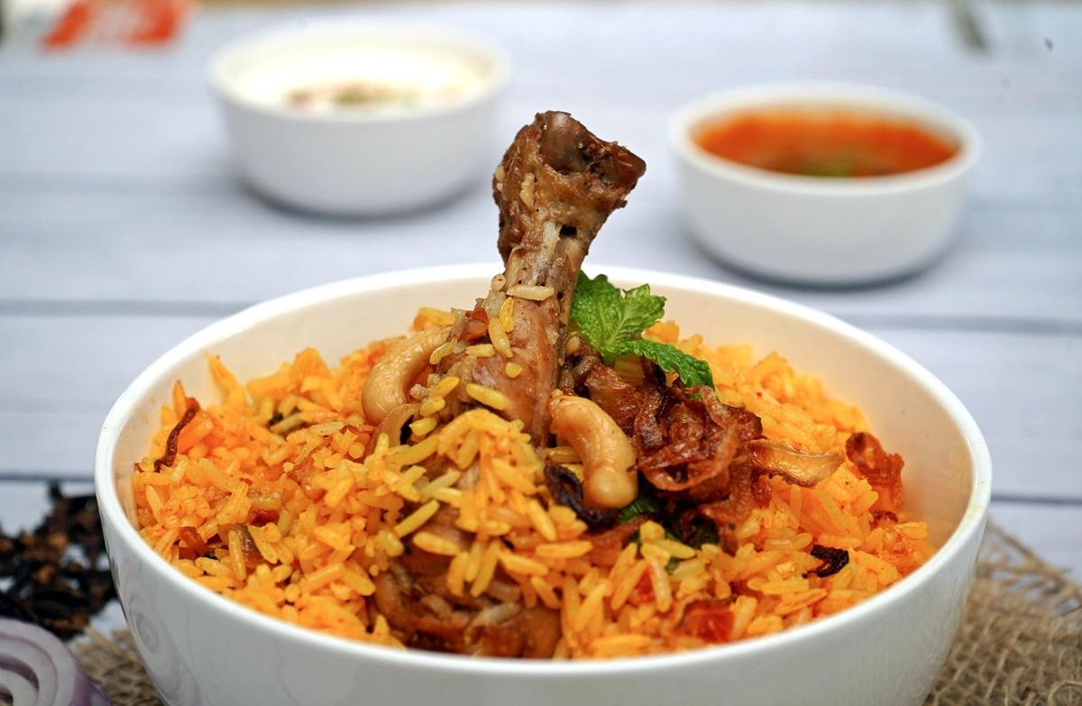 A modest bowl of biryani measured next to a large wedding-style serving