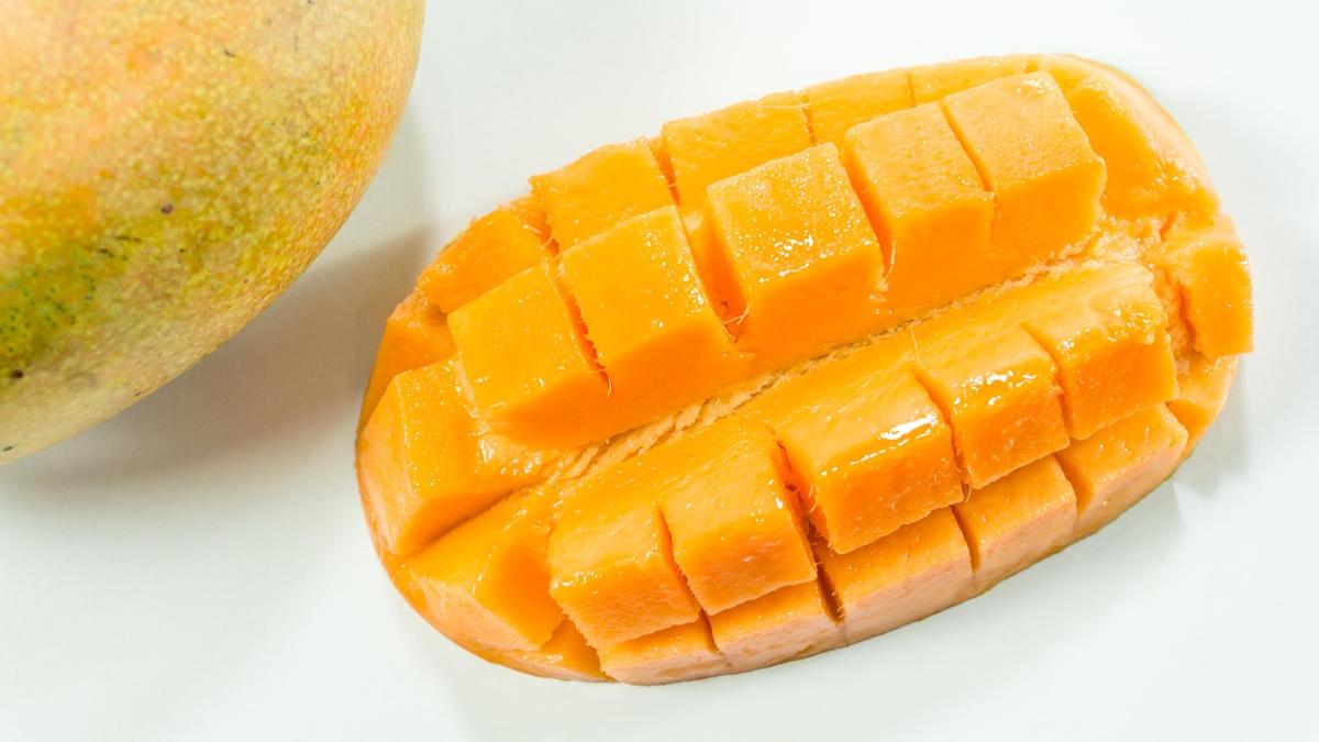 Diced mango measured into a small bowl next to a whole mango