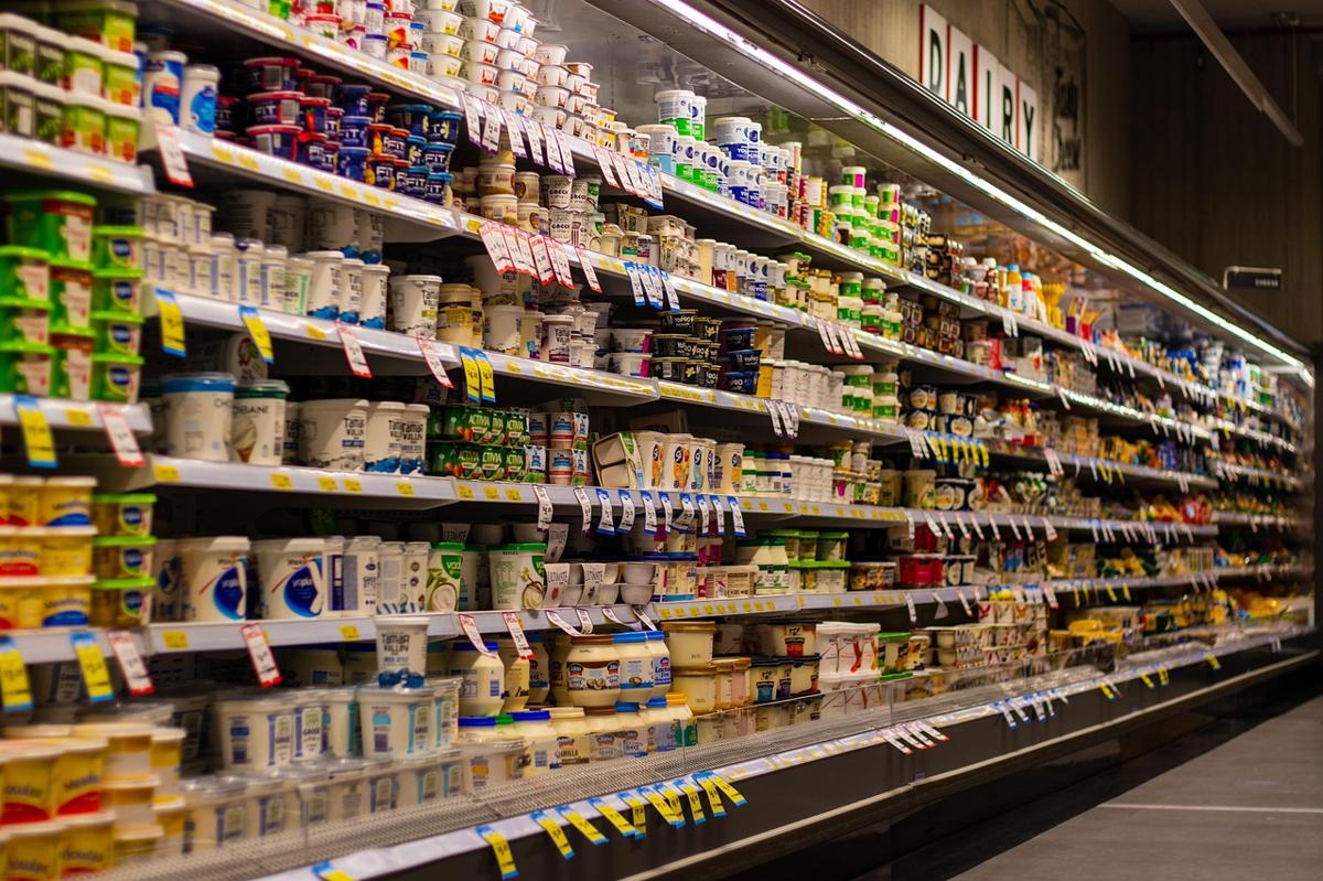 Pakistani grocery table showing whole wheat chakki atta bag, plain dahi tub, roasted almonds, and unsweetened tea