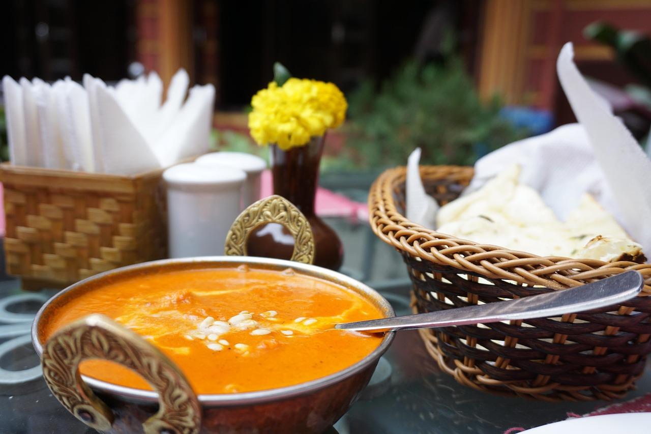 A lavish restaurant table spread with Nihari, Haleem, Naan, and sweet drinks
