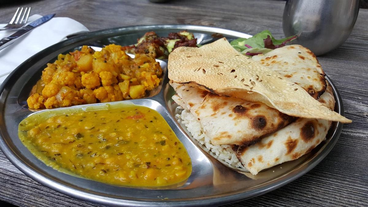 A roti served with daal, a vegetable curry, and a side salad